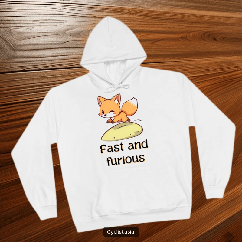 Funny hoodie with a playful fox character, wind in its tail, zooming down a small hill. Cozy and full of energy.